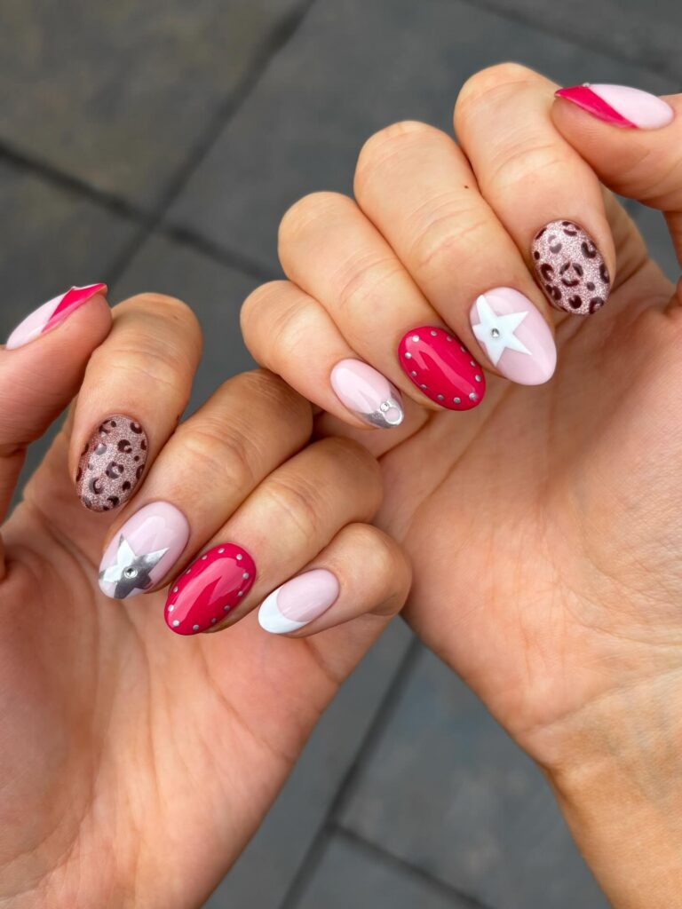 Colorful spring nails with pink, white, and metallic designs, featuring stars and leopard print patterns. Credits: @thenaillologist