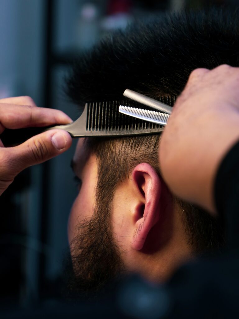 [ALT_TEXT: A close-up of a barber cutting a mullet for a customer, carefully shaping the sides.]