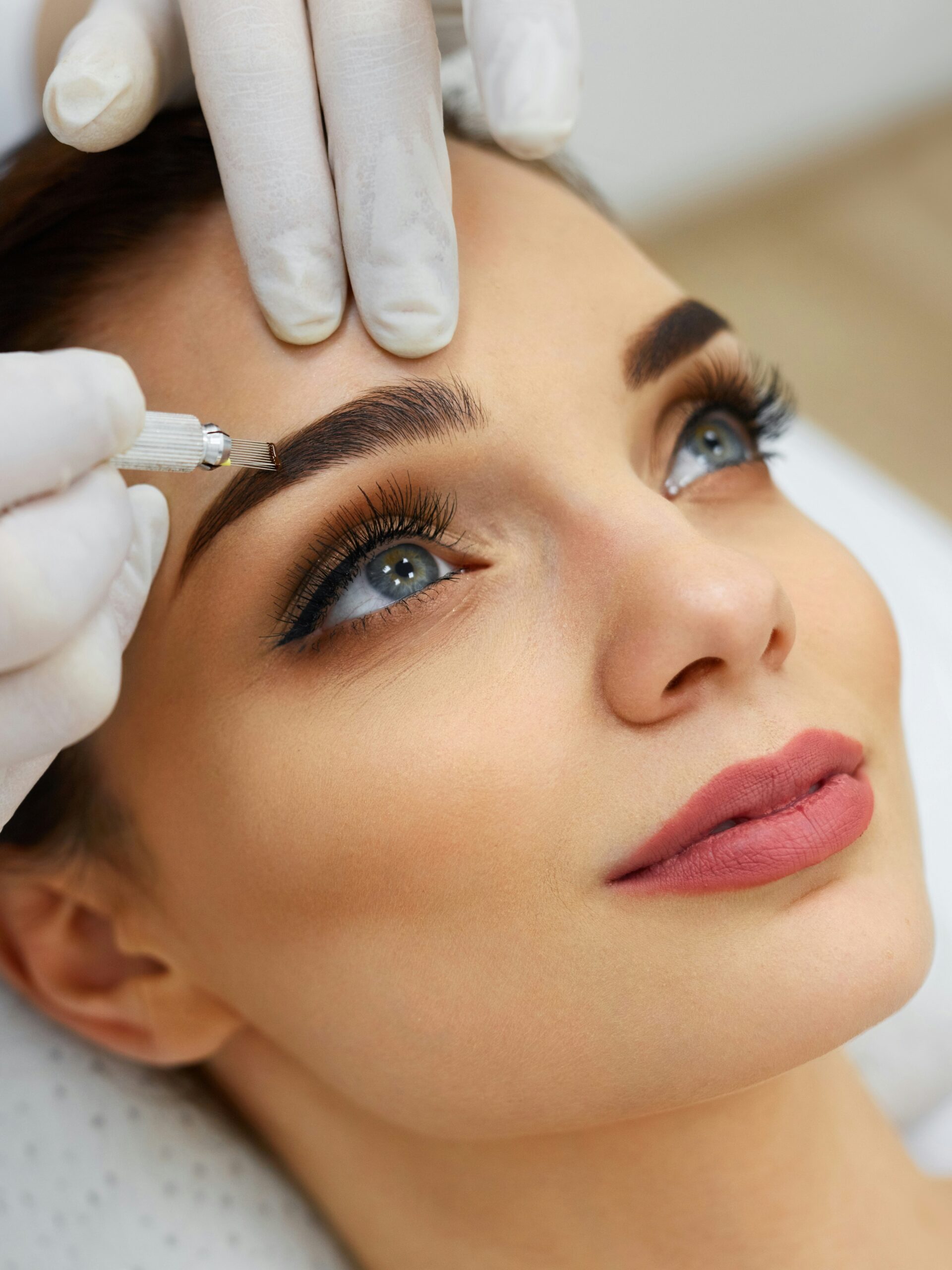 A close-up of a woman’s face in a salon receiving a microblading treatment