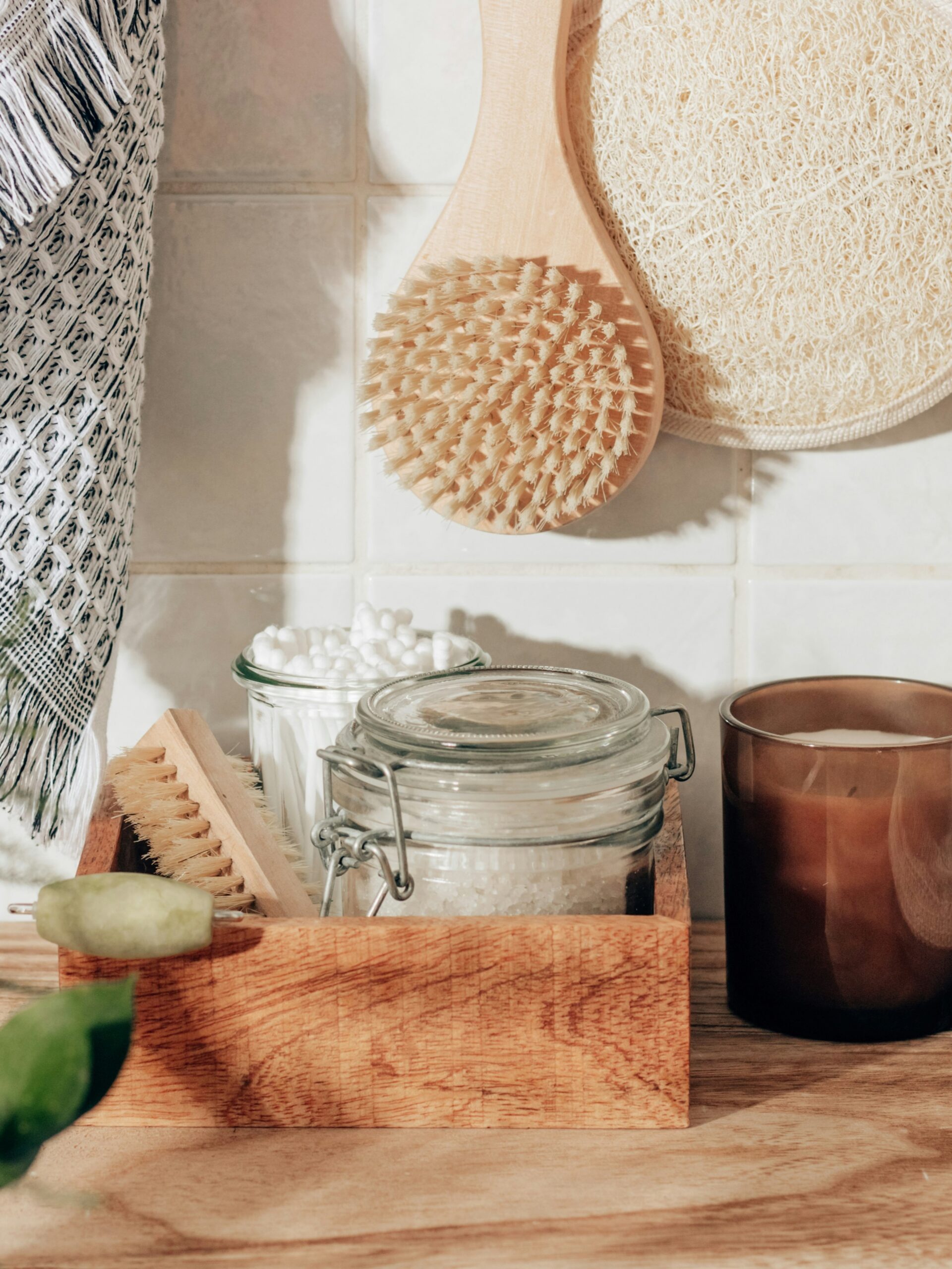 Styled shot of bathroom accessories, including an exfoliating mitt, body brush, bath salts, cotton buds and a candle