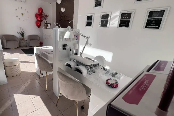 White nail salon at Sara Nails&Beauty in Tortolì with grey velvet chairs and framed certificates on the wall.